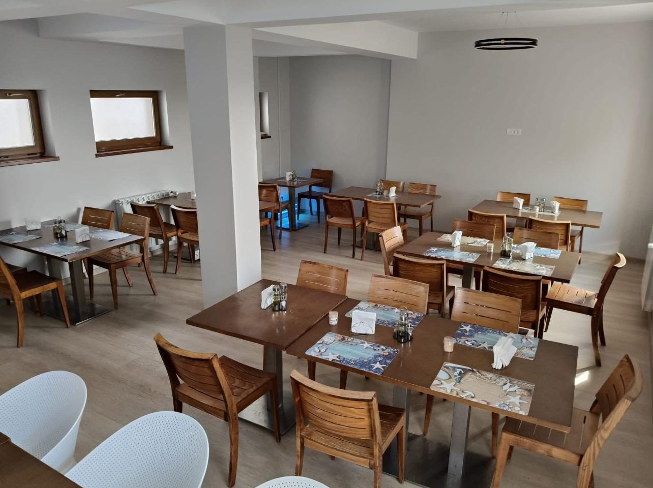 Restaurantul hotelului, cu mese din lemn și scaune albe