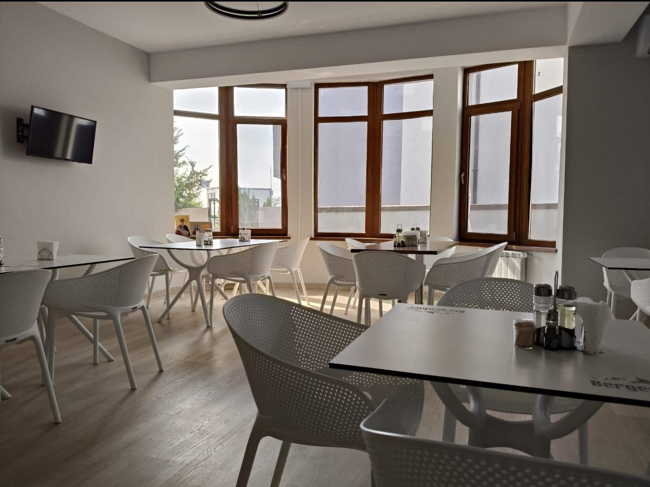 Restaurantul hotelului, luminos, cu mese și scaune albe